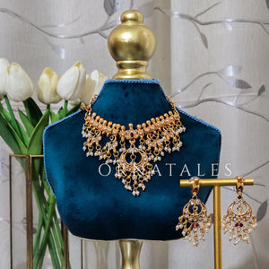 South Indian choker necklace in matte gold with circular red and white stone motif, pearl and gold bead fringes, intricate temple filigree, and matching earrings.
