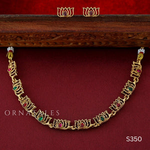 Rajnandini Lotus Garland Necklace Set featuring alternating lotus motifs with emerald and pink kundan stones, antique gold finish, and matching earrings.