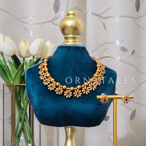 Floral motif choker necklace with ruby and emerald stones, gold base, ball-bead spacers, and matching stud earrings.