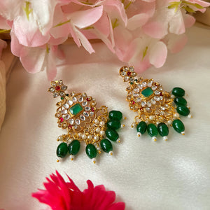 Temple-inspired Emerald Kumuda necklace set featuring green teardrop stones, red kundans, and a center emerald-cut stone.