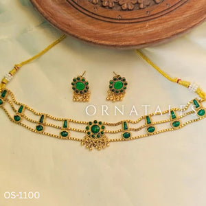Traditional emerald kundan choker with crescent pendant, pearl hangings, antique gold finish, and matching earrings.