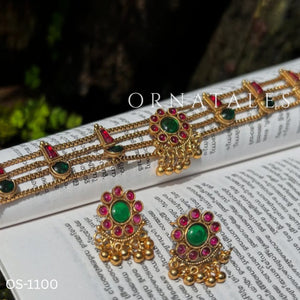 Traditional ruby emerald kundan choker with crescent pendant, pearl hangings, antique gold finish, and matching earrings.