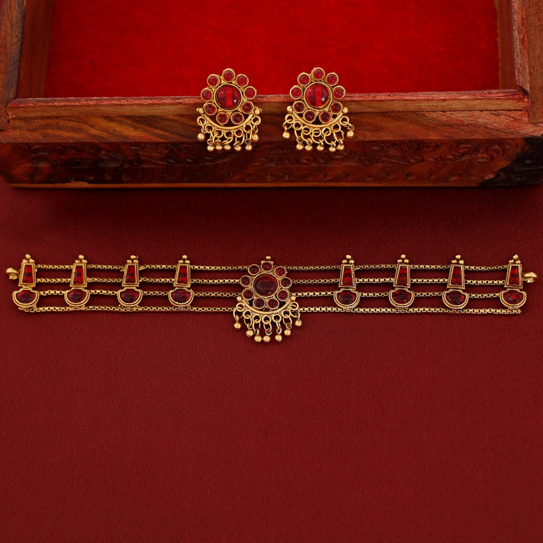 Traditional ruby kundan choker with crescent pendant, pearl drops, antique gold finish, and matching earrings.