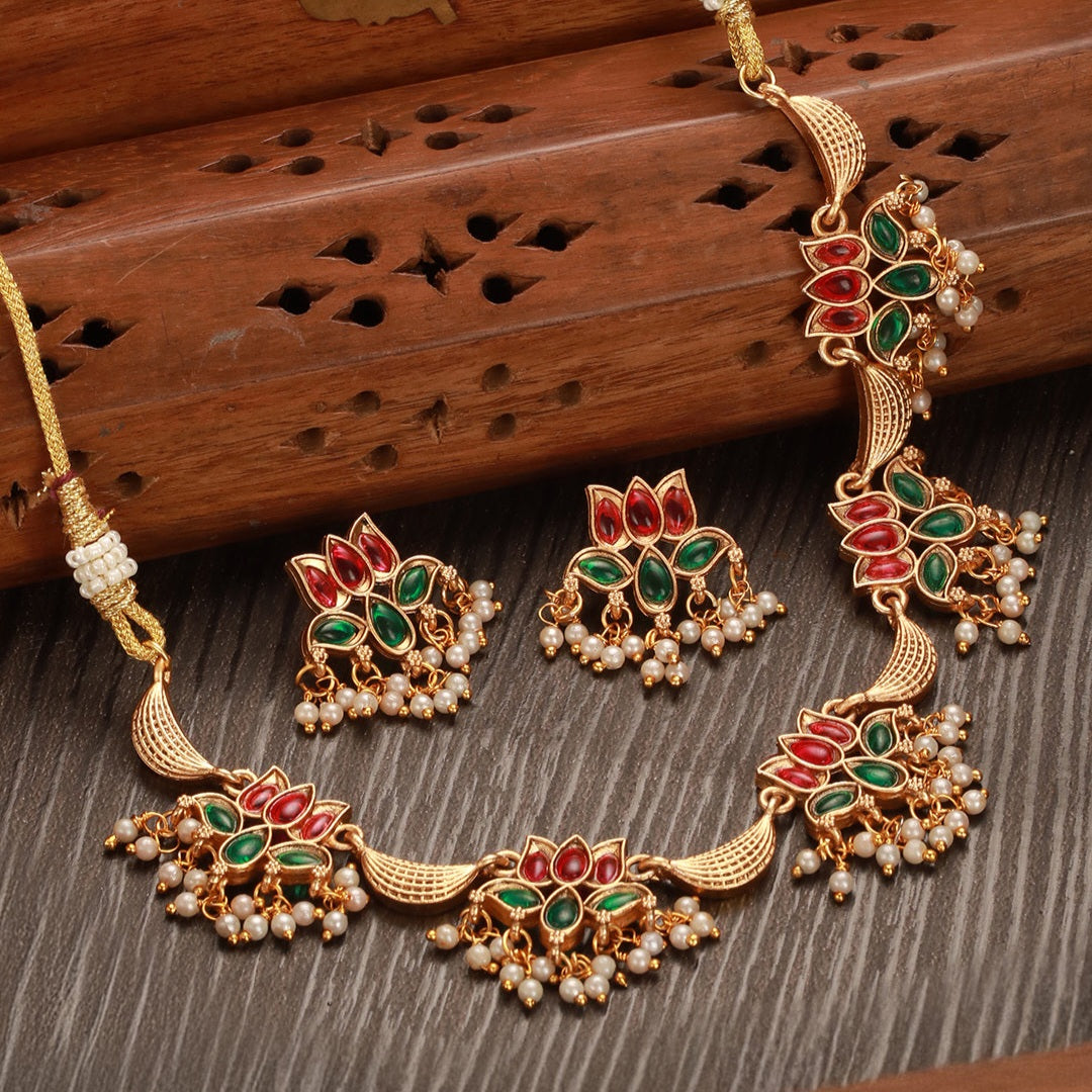Mrinalika Lotus Cascade Necklace Set featuring ruby and emerald kundan lotus motifs, layered pearl hangings, and matching earrings.