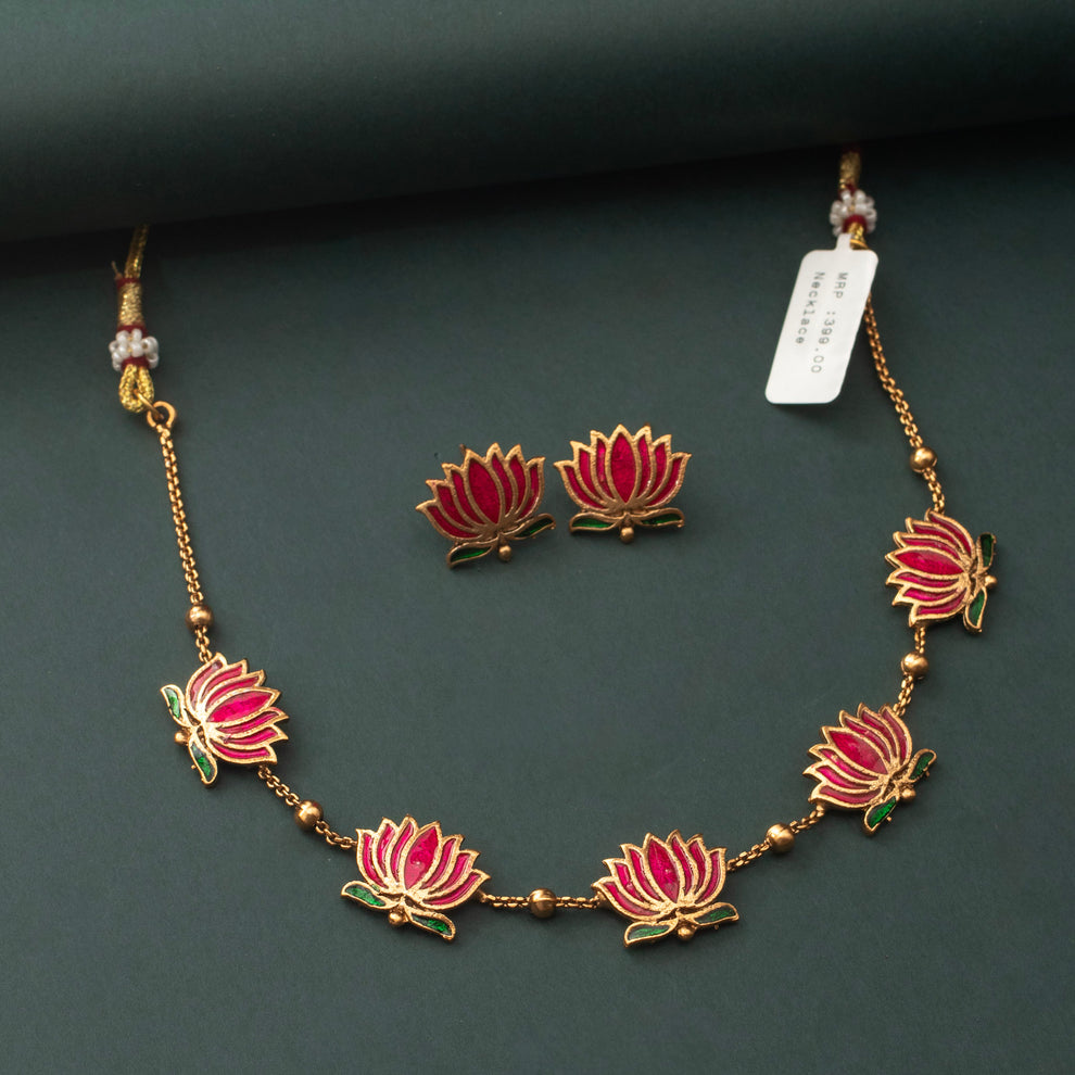 Padmavathi Blossom choker set with ruby enamel lotus motif, emerald green leaves, and gold link chain featuring matching stud earrings.