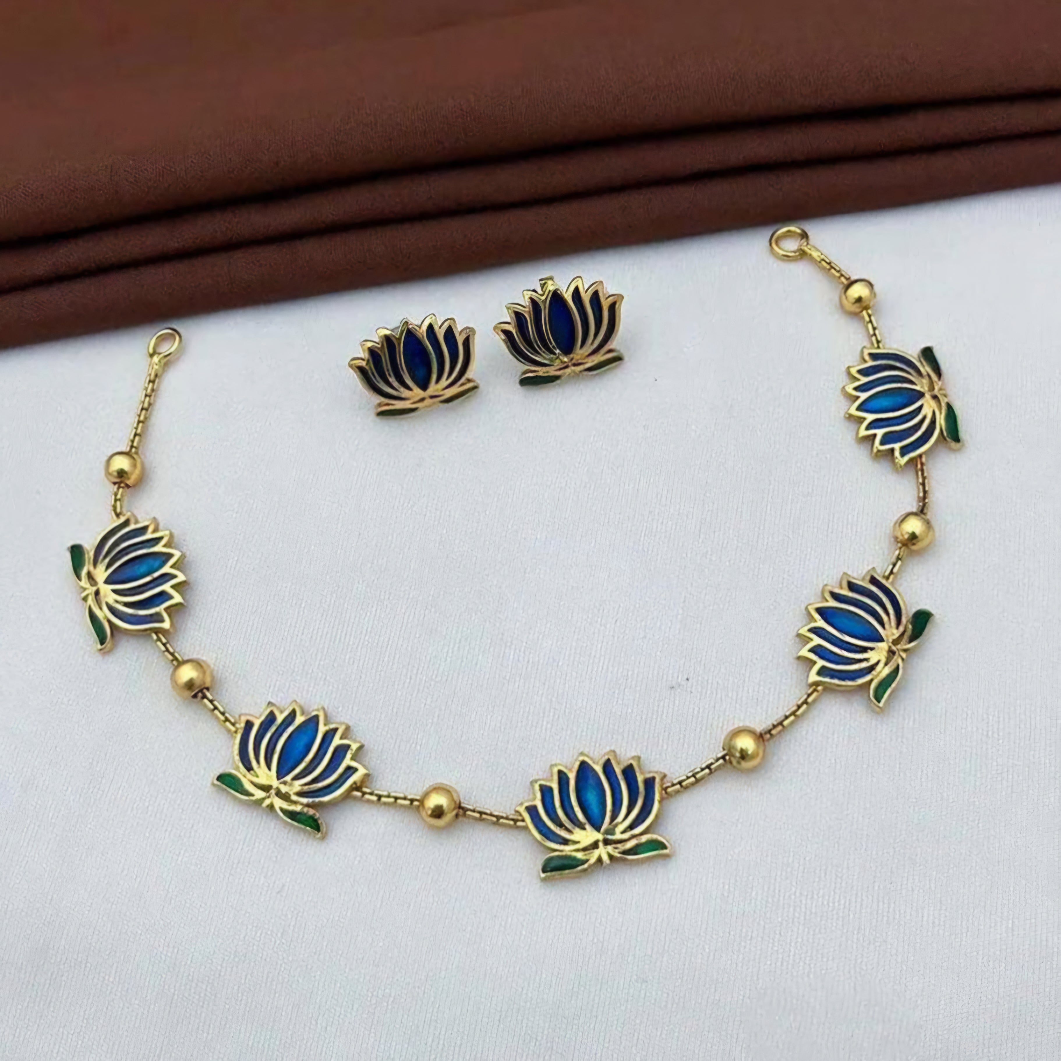Padmavathi Blossom choker set with blue enamel lotus motif, emerald-green leaves, and gold link chain featuring matching stud earrings.
