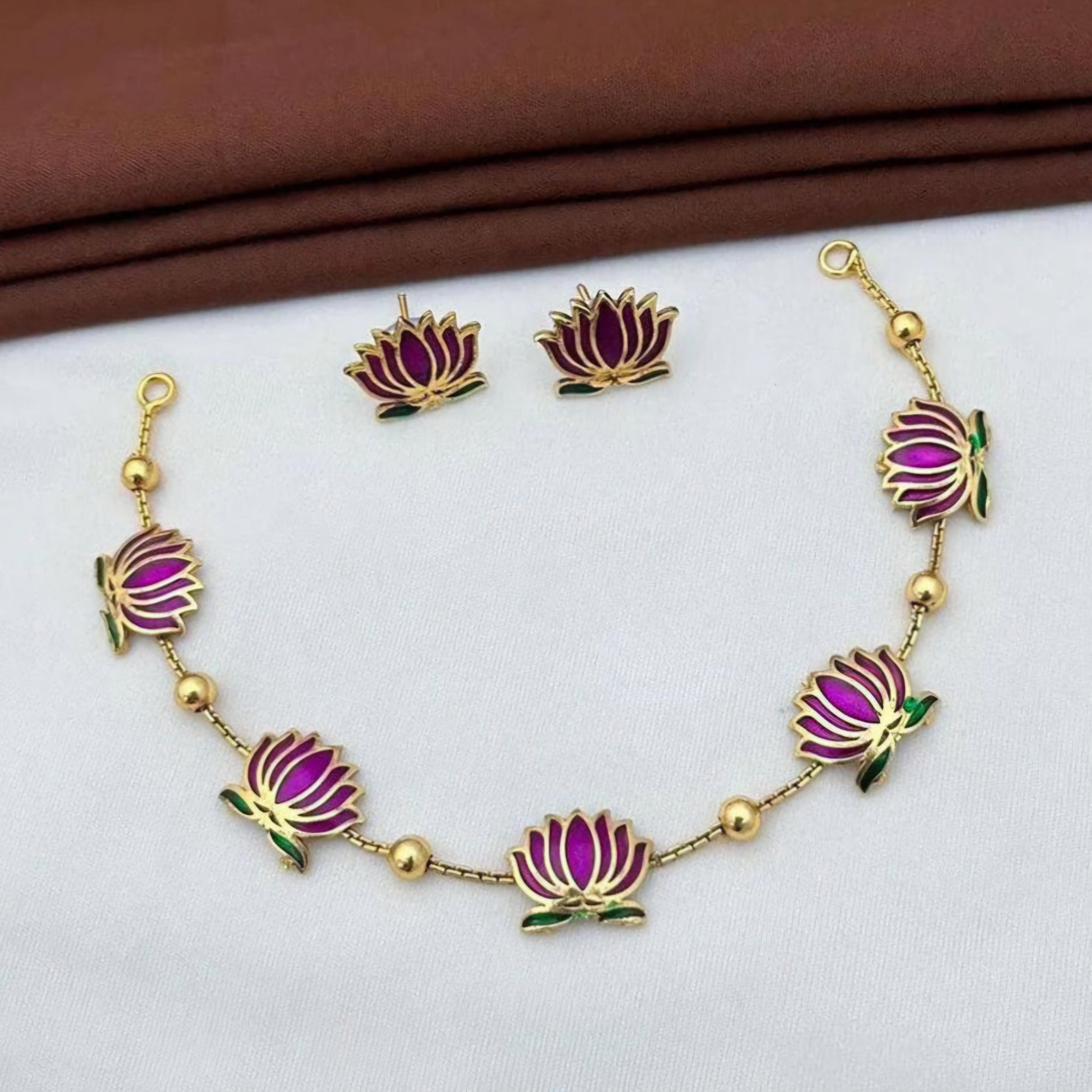 Padmavathi Blossom choker set with magenta enamel lotus motif, emerald green leaves, and gold link chain, paired with matching stud earrings.