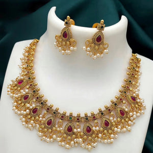 Matte gold South Indian necklace with ruby teardrop stones, white pearls, and matching earrings featuring pearl fringe detailing.