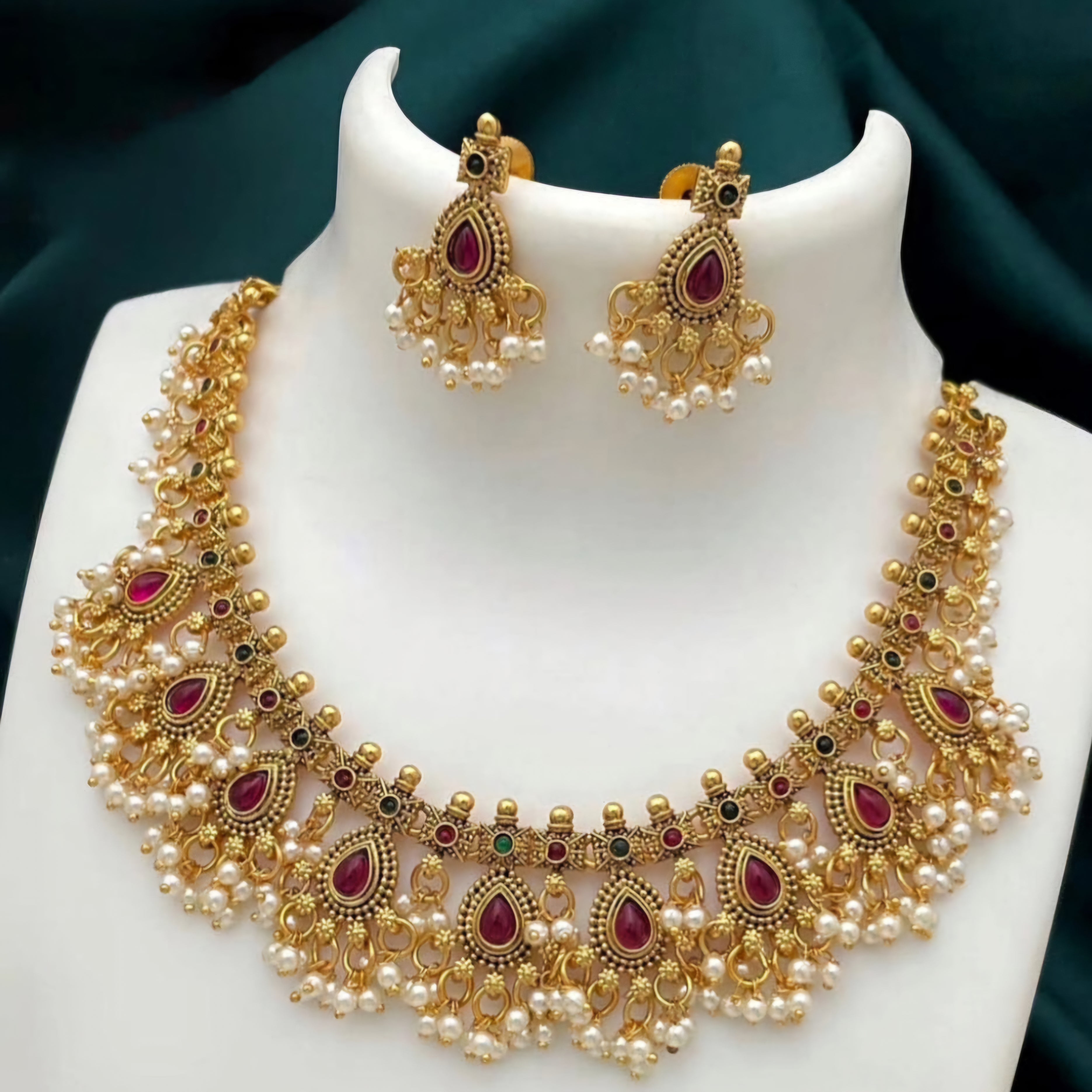 Matte gold South Indian necklace with ruby teardrop stones, white pearls, and matching earrings featuring pearl fringe detailing.