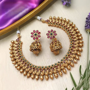 Traditional antique gold Kanakavalli necklace set handcrafted with round gold beads and mini kundan insets, paired with floral motif earrings.