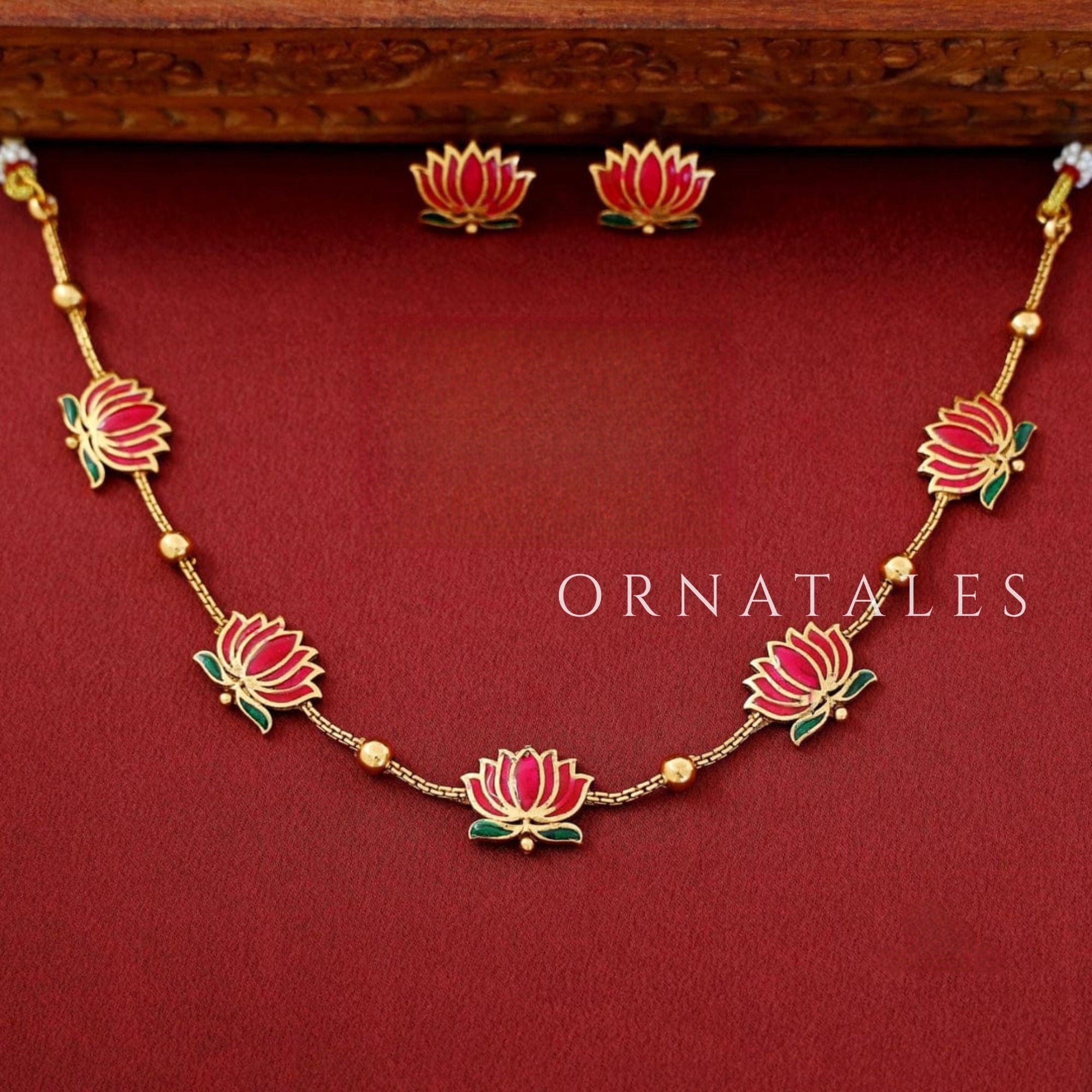 Padmavathi Blossom choker set with ruby enamel lotus motif, emerald green leaves, and gold link chain featuring matching stud earrings.