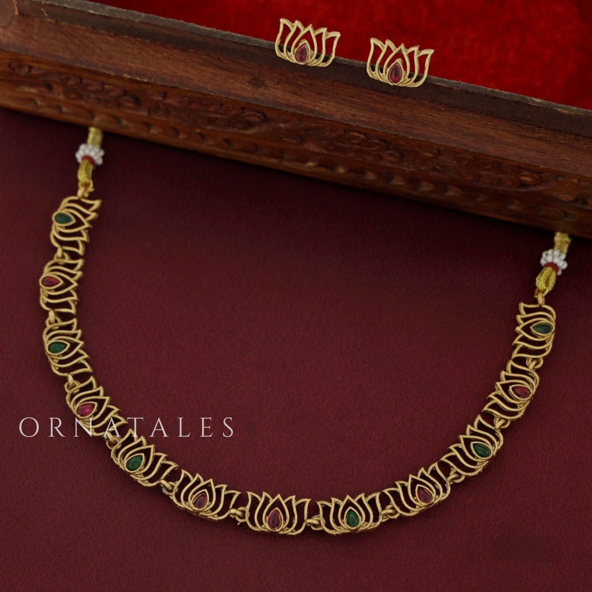 Rajnandini Lotus Garland Necklace Set featuring alternating lotus motifs with emerald and pink kundan stones, antique gold finish, and matching earrings.