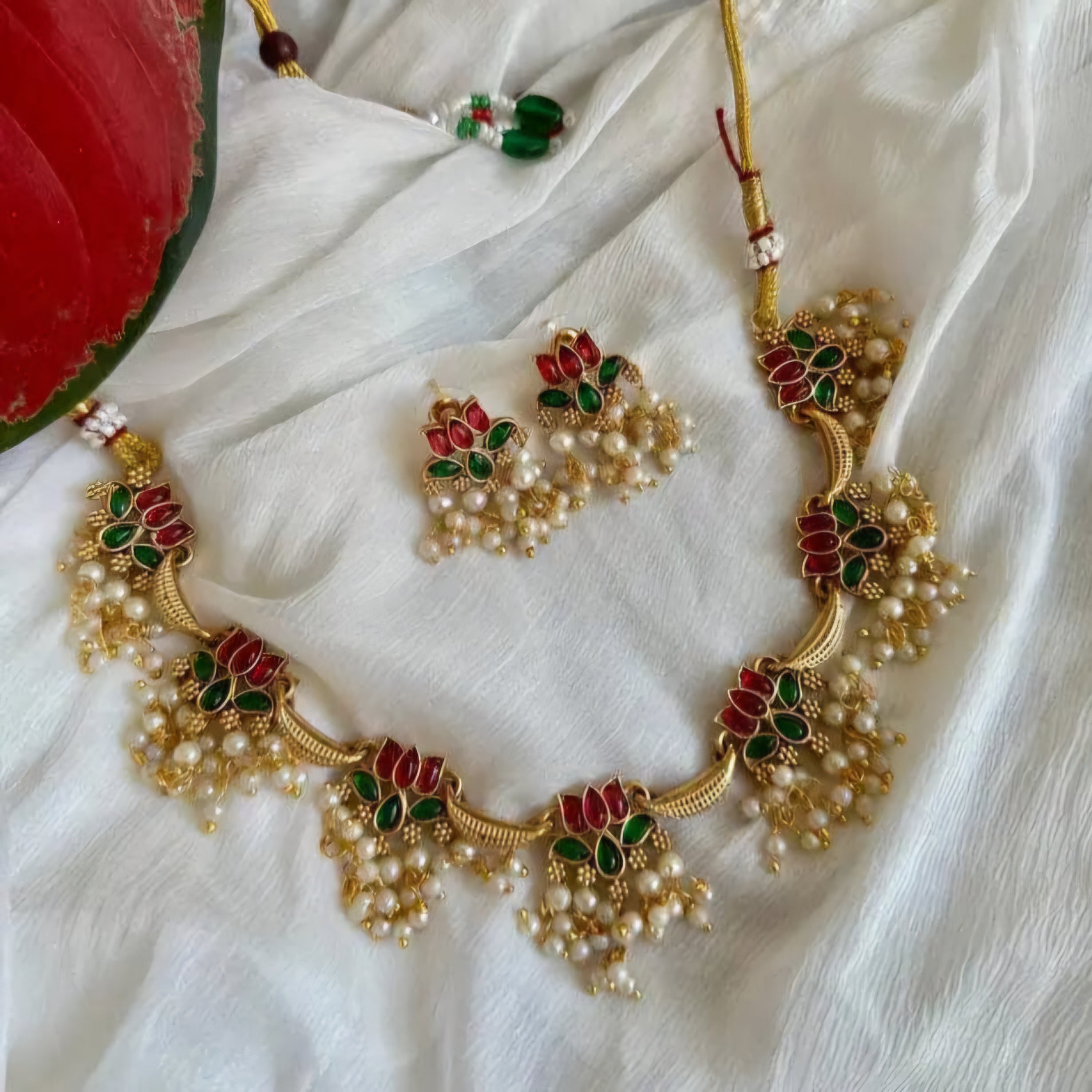 Anuragini Pearl Lotus Choker Set with ruby and emerald kundan lotus motifs, pearl fringe detailing, and matching earrings.