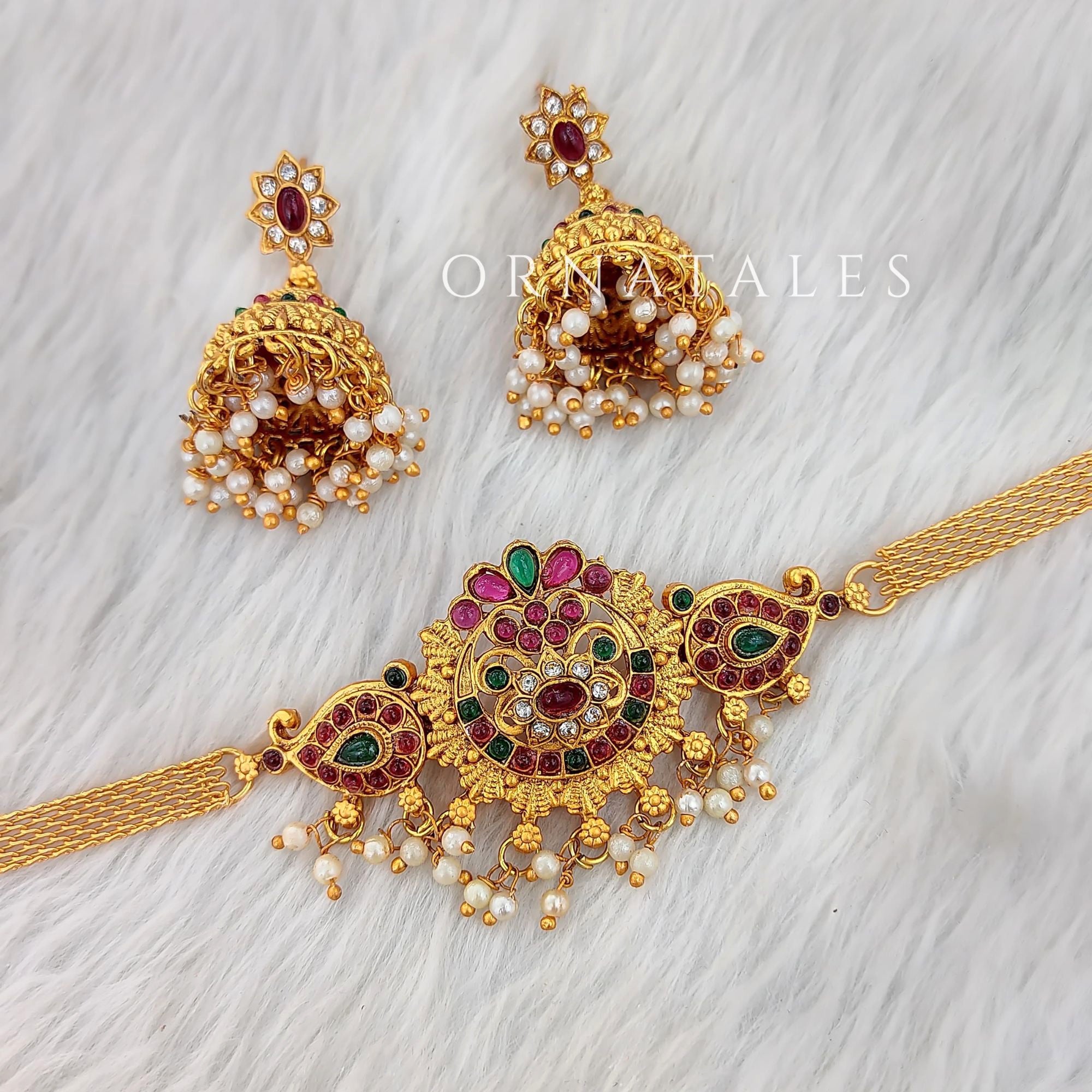 Matte gold South Indian choker with mandala-inspired centerpiece, ruby, green & white stones, pearl drops, and matching floral dome jhumka earrings.
