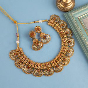Matte gold South Indian choker with blossom-inspired motifs, ruby and green stones, filigree detailing, golden bead edging, and matching earrings.