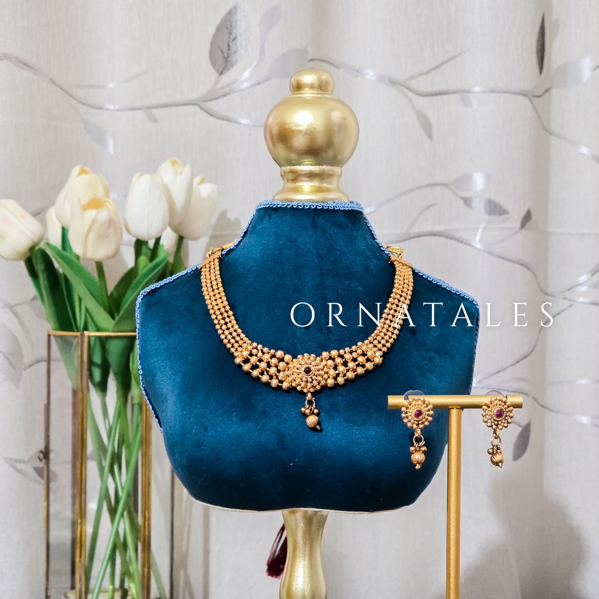 Rudrakshika temple choker necklace with triple golden bead layers, ruby lotus motif centerpiece, and miniature drop pendant detailing.