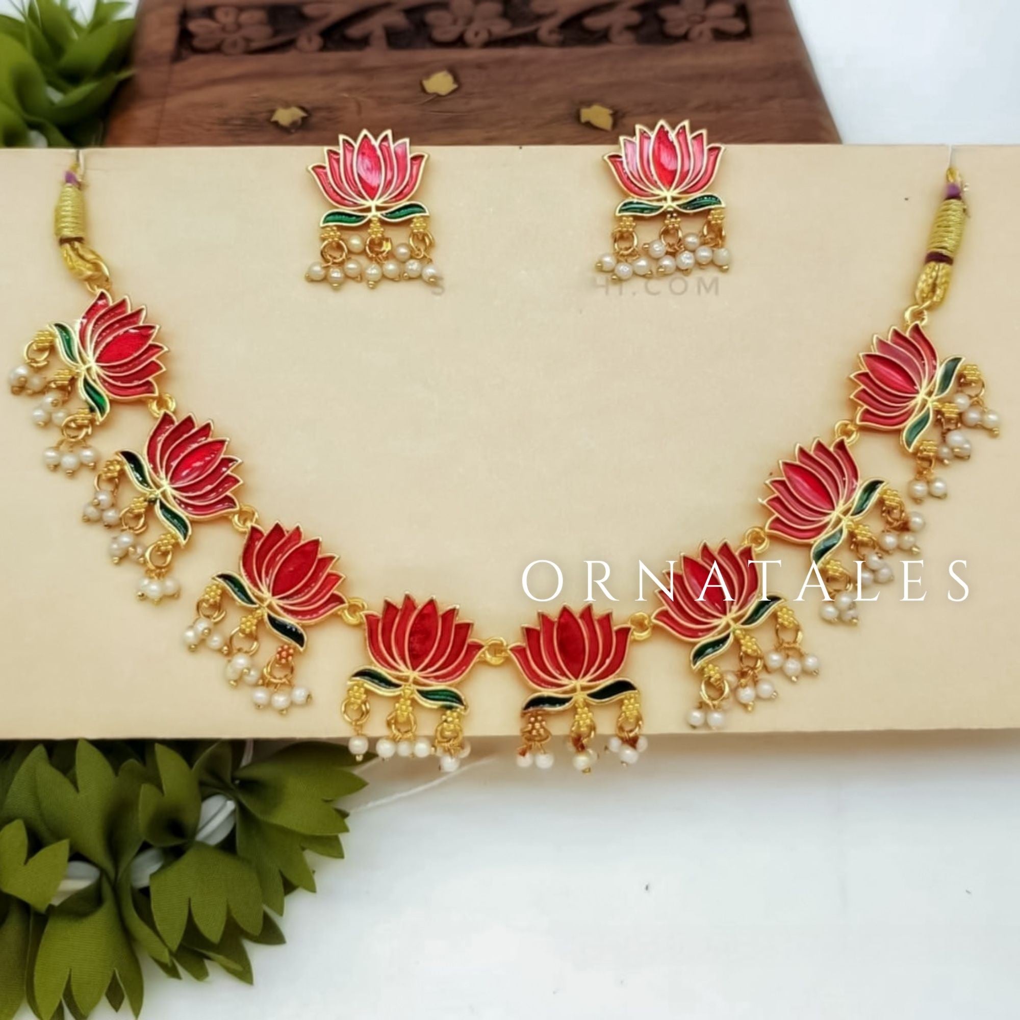 Kamalini Pearl Drop Choker Set with ruby-gold lotus motifs, hanging pearl clusters, and matching lotus drop earrings in a temple-inspired design.