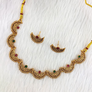 South Indian choker necklace with arched segments, red and green stones, micro-bead detailing, matte gold finish, and matching half-arch earrings.