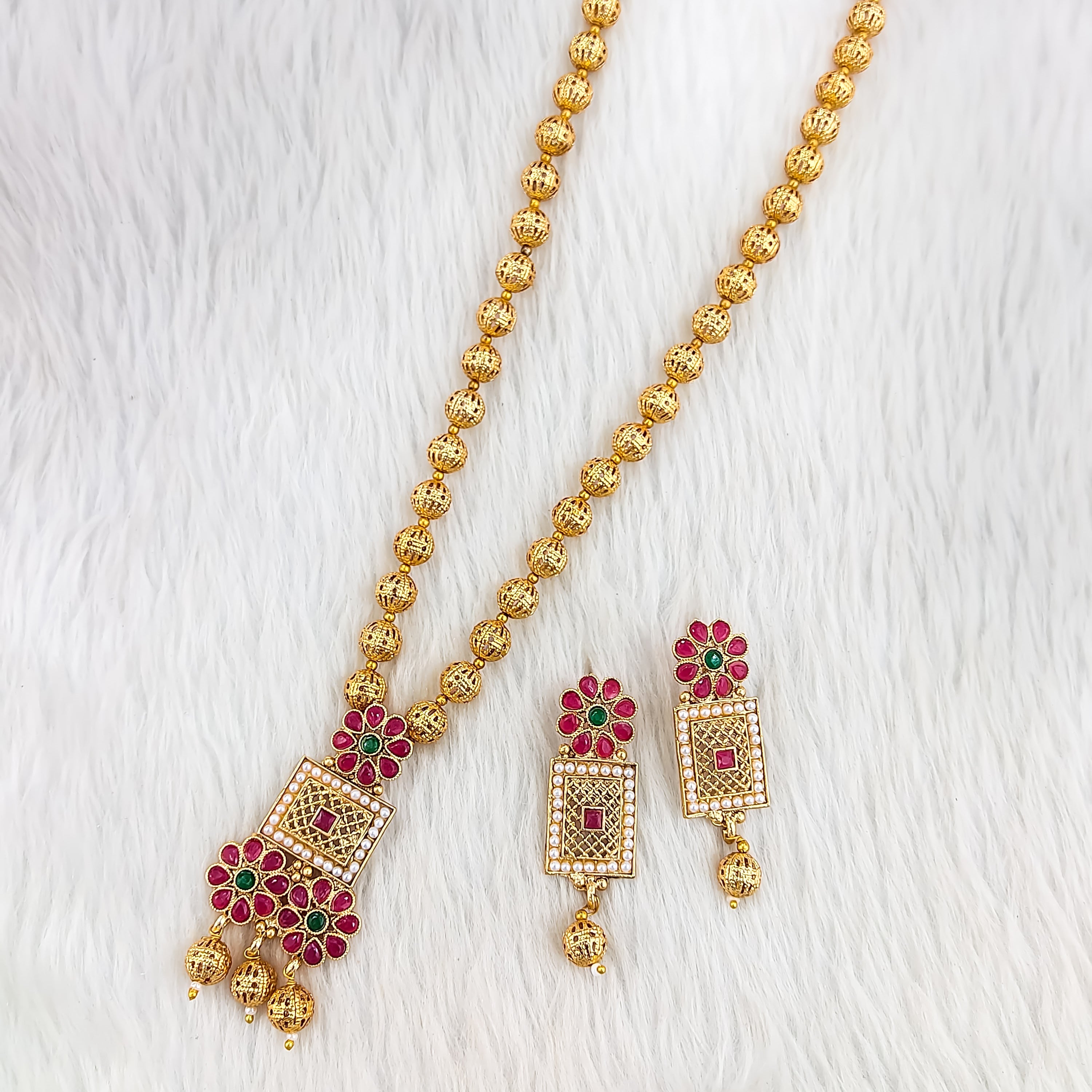 South Indian Sita necklace with ruby and white stones, square blossom pendants, red petal floral motifs, matte gold bead chain, and matching rectangular drop earrings.