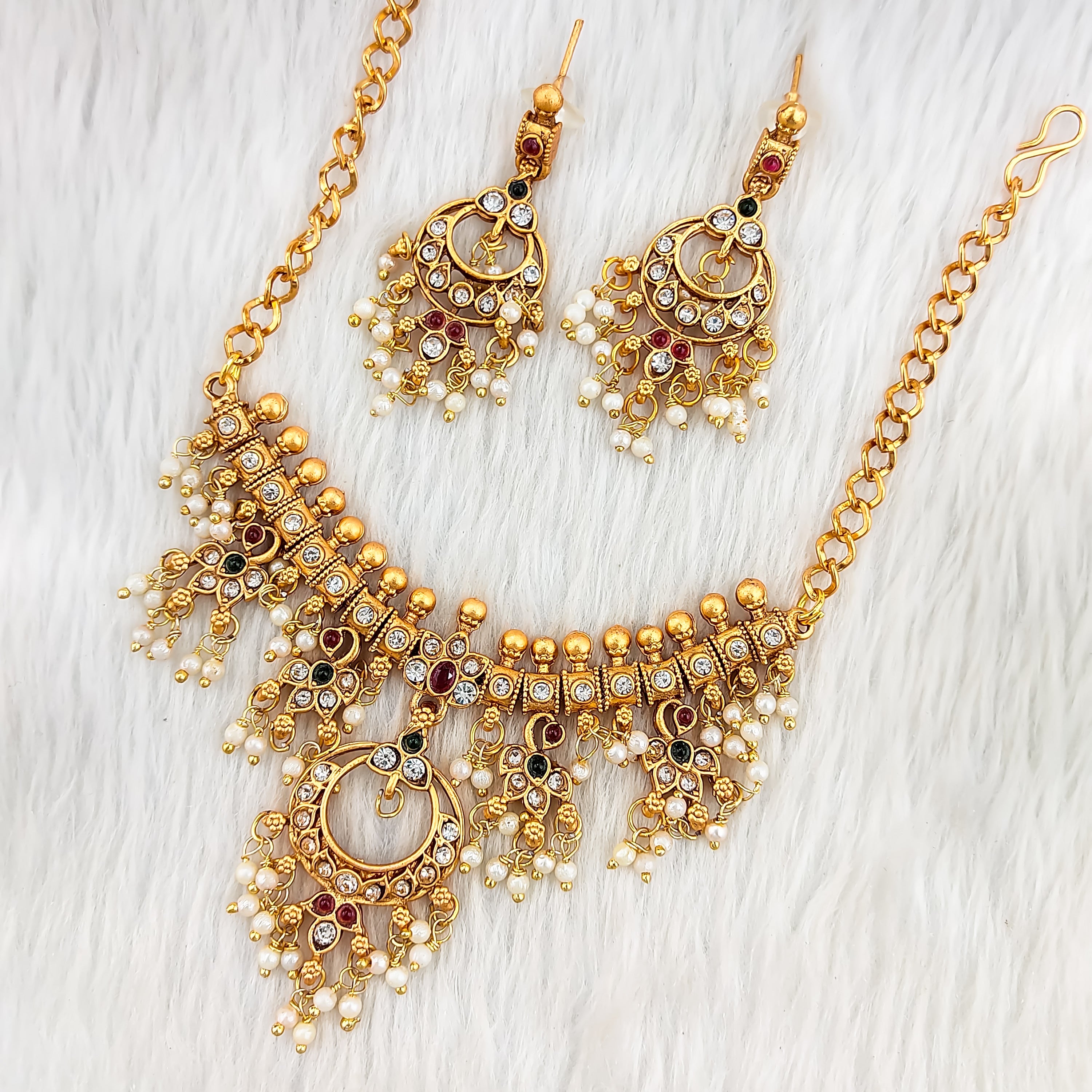 South Indian choker necklace in matte gold with circular red and white stone motif, pearl and gold bead fringes, intricate temple filigree, and matching earrings.