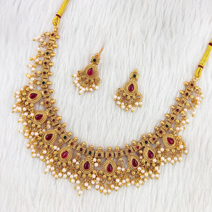 Matte gold South Indian necklace with ruby teardrop stones, white pearls, and matching earrings featuring pearl fringe detailing.