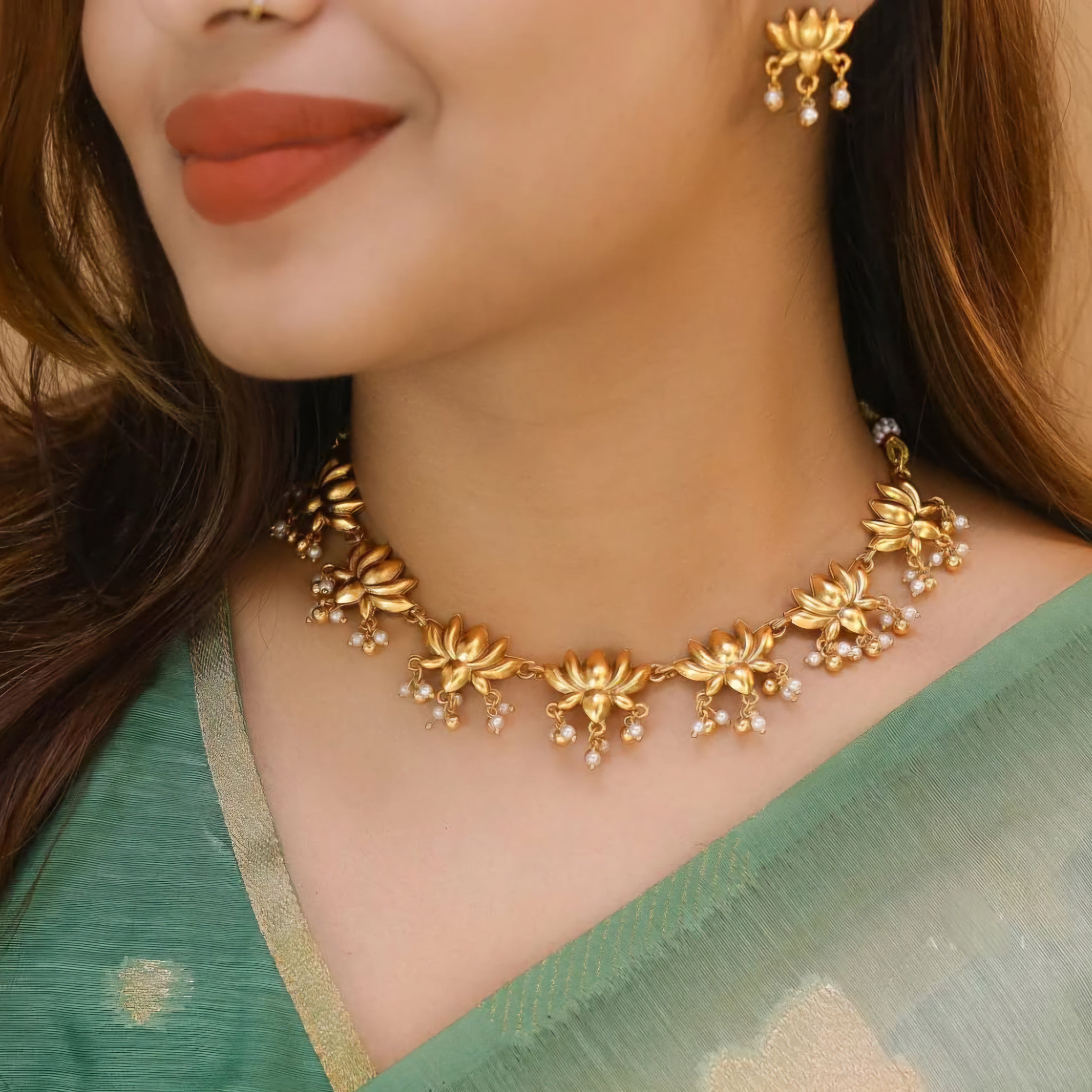 Suvarna Padmakshi Necklace Set with matte gold lotus motifs, dangling pearl details, and matching earrings in traditional temple-inspired design.