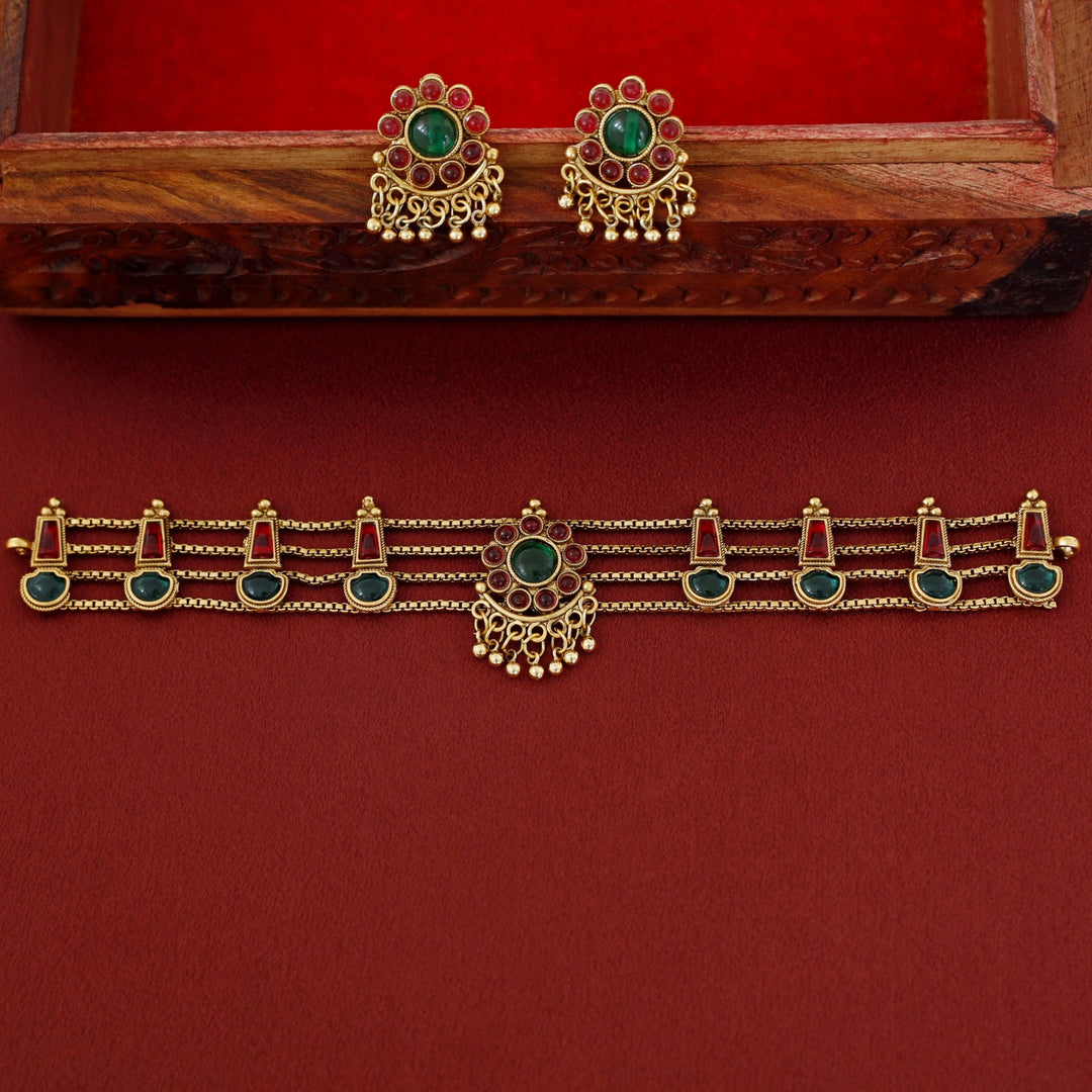 Traditional ruby emerald kundan choker with crescent pendant, pearl hangings, antique gold finish, and matching earrings.