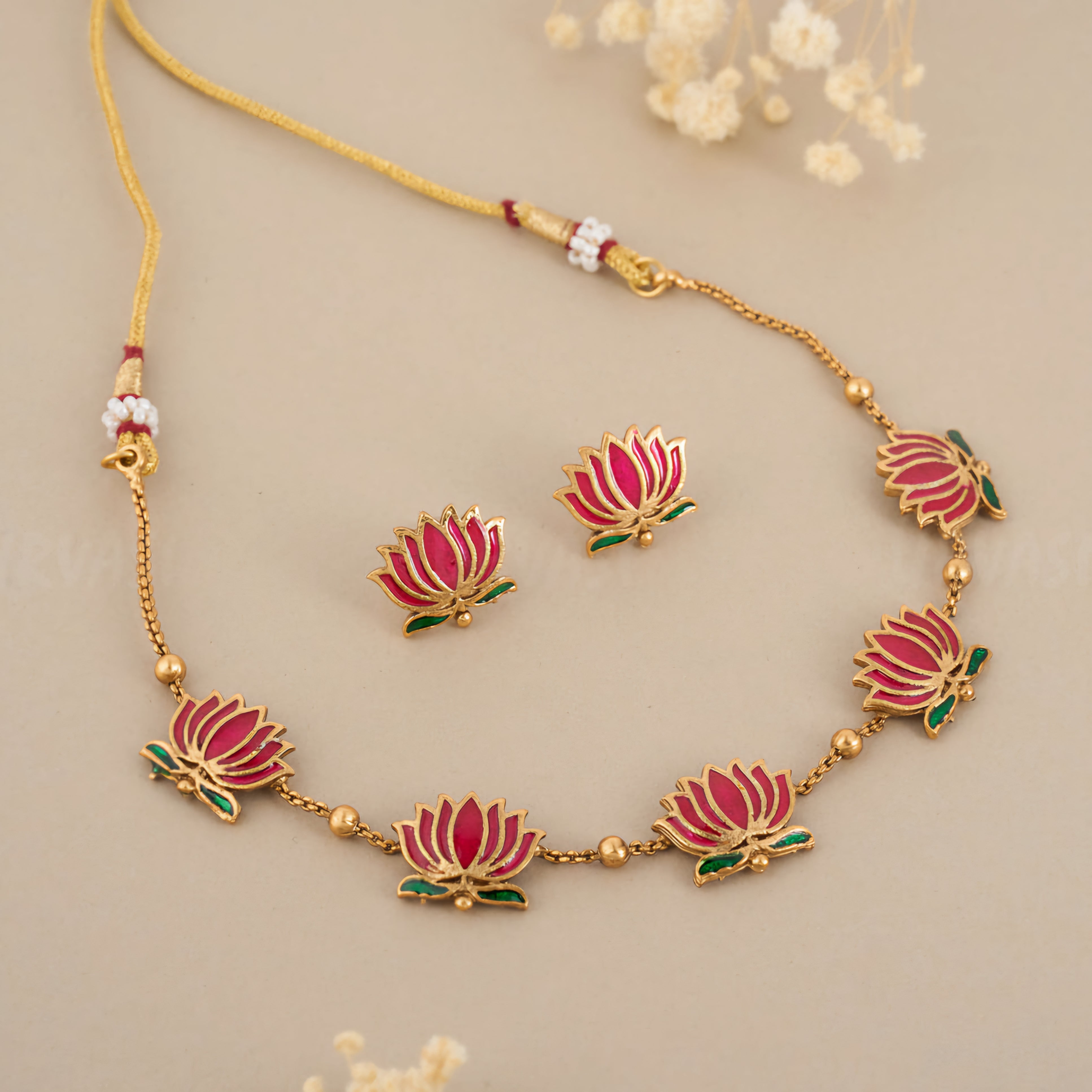 Padmavathi Blossom choker set with ruby enamel lotus motif, emerald green leaves, and gold link chain featuring matching stud earrings.
