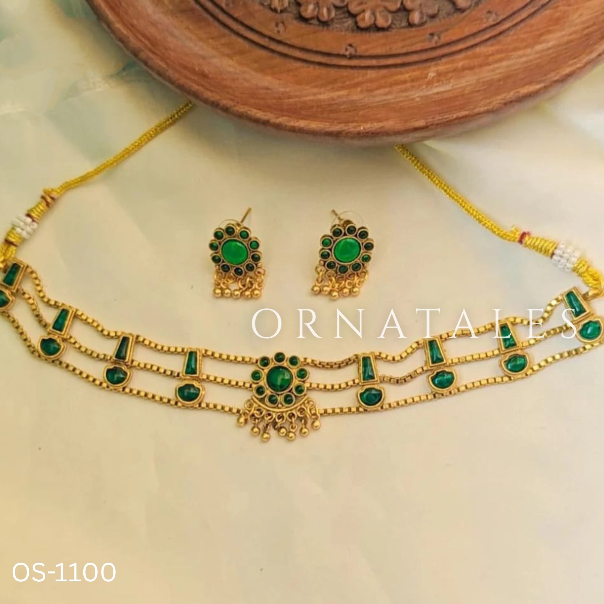 Traditional emerald kundan choker with crescent pendant, pearl hangings, antique gold finish, and matching earrings.