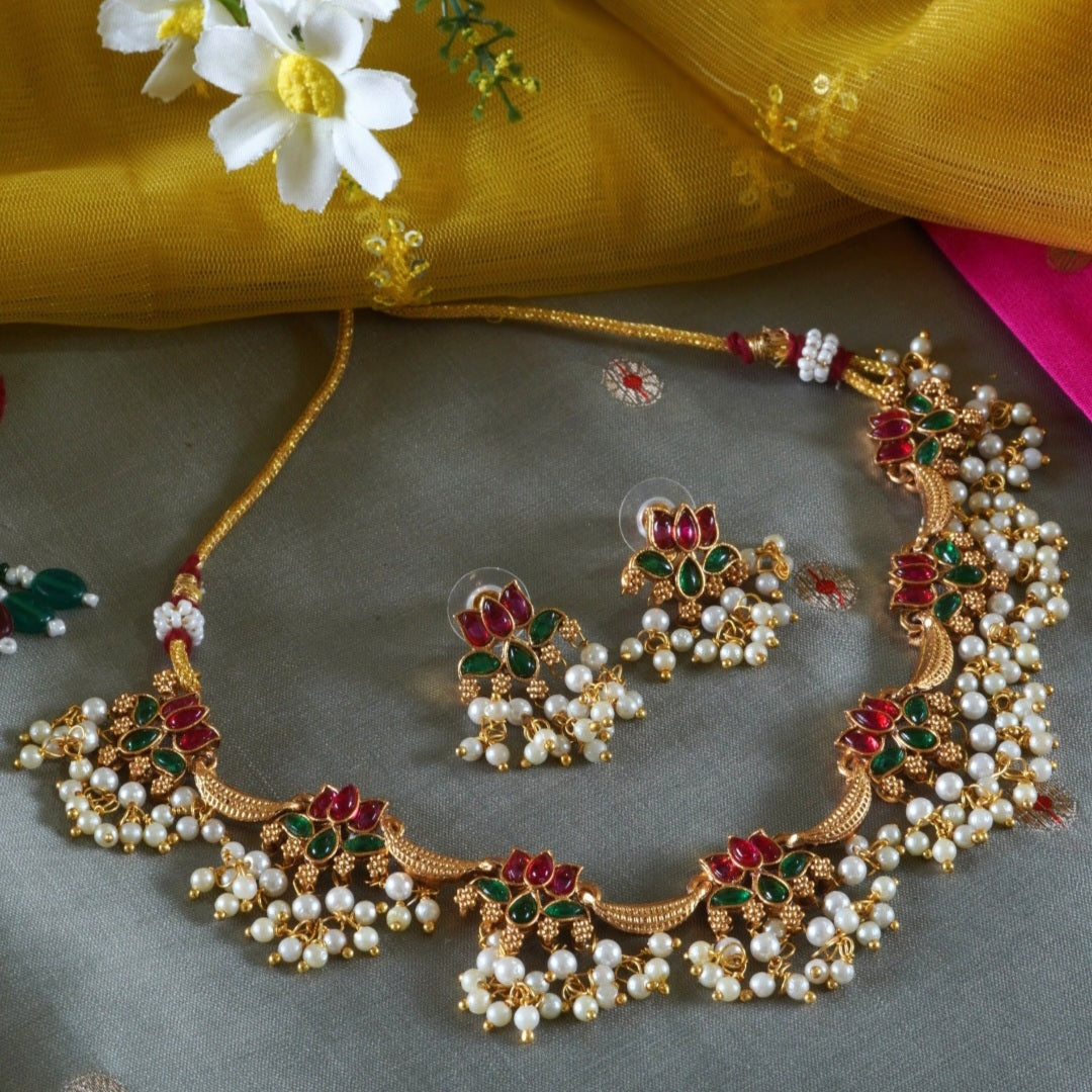 Anuragini Pearl Lotus Choker Set with ruby and emerald kundan lotus motifs, pearl fringe detailing, and matching earrings.