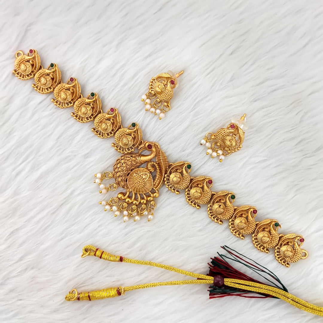 Matte gold South Indian choker necklace with temple-style peacock motifs, pearl droplets, central peacock pendant, and matching earrings.