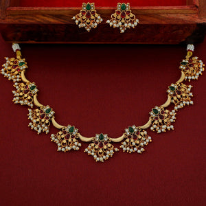 Gold necklace with green and red stones on a red background