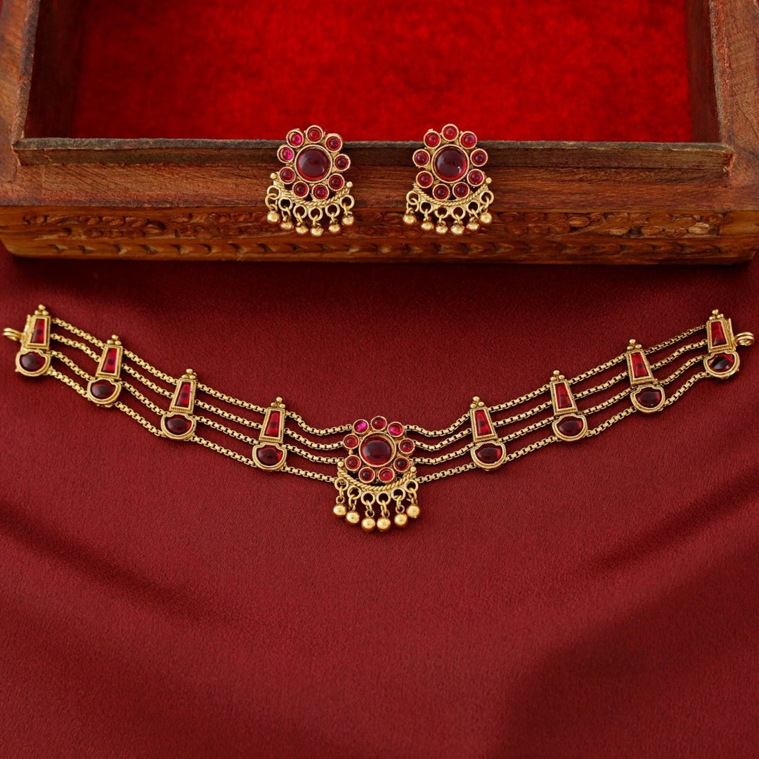 Traditional ruby kundan choker with crescent pendant, pearl drops, antique gold finish, and matching earrings.